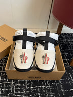 White and black winter boots with black ankle straps and red logo patches
