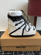 White and black lace-up snow boots with strap accents and padded ankle collar