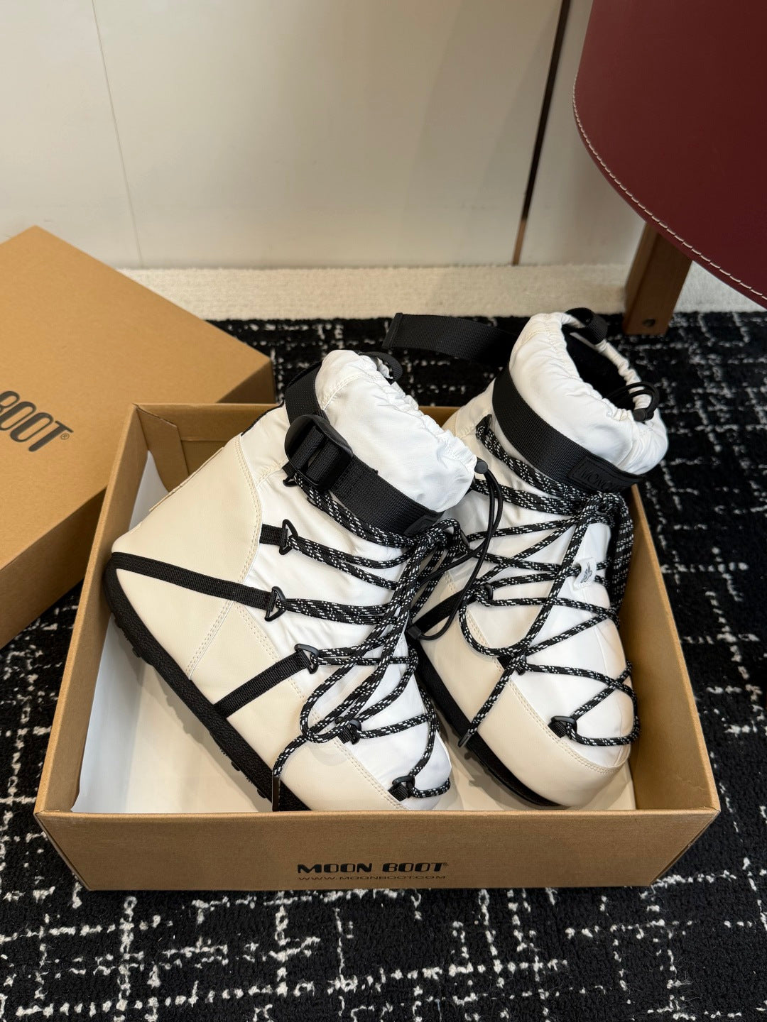 Pair of white lace-up winter boots with black straps and padded top cuffs
