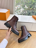 Brown leather lace-up boots with thick black sole, angled pair view