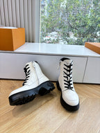 White leather ankle boots with black lace-up front and chunky rubber outsoles