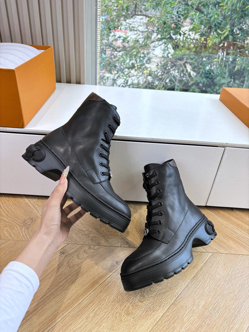 Louis Vuitton unisex lace-up boots, black leather; hand holds one boot