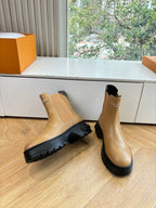 Tan leather Chelsea boots with elastic sides and thick black rubber sole.