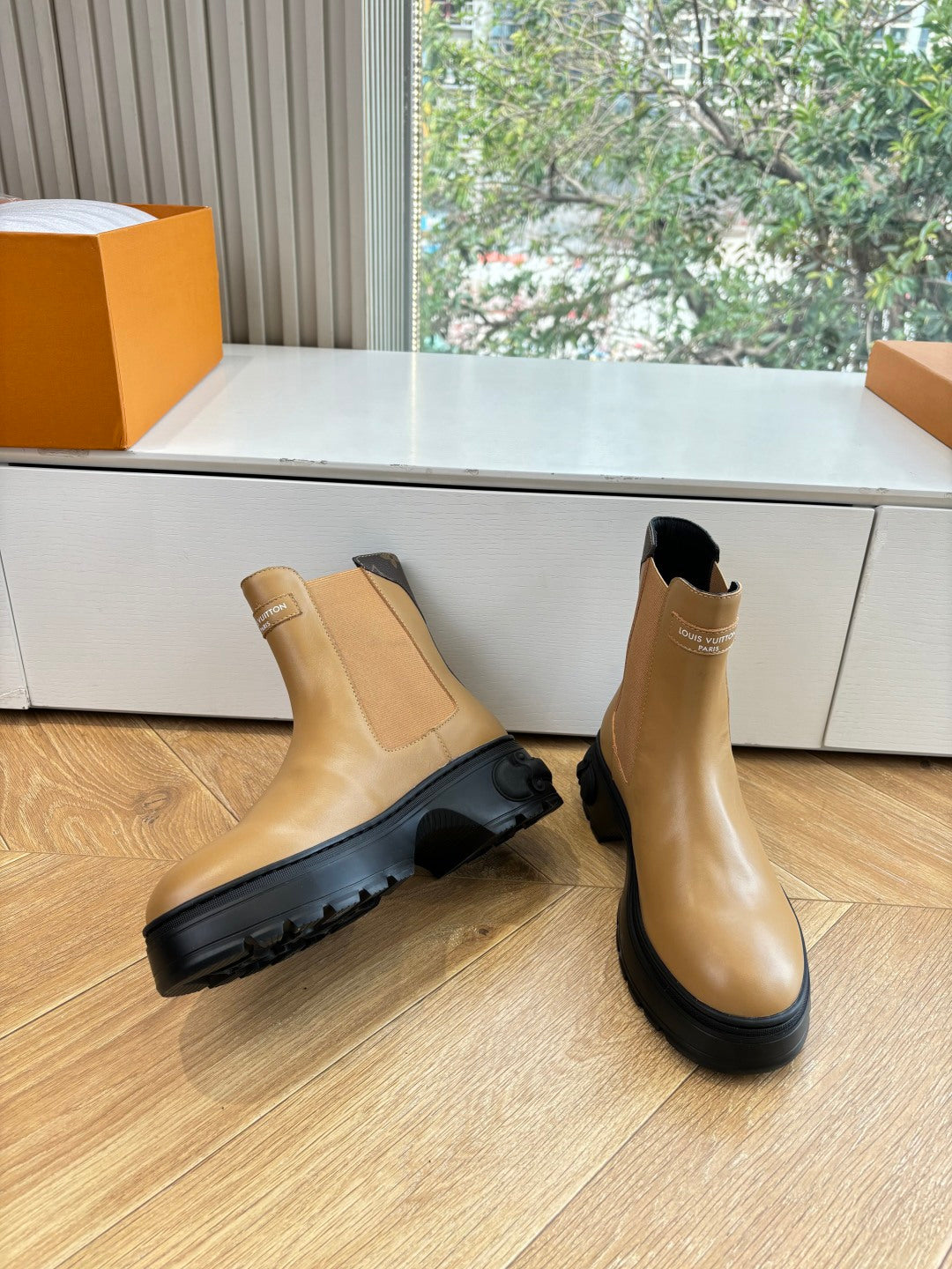 Tan leather Chelsea boots with elastic sides and thick black rubber sole.