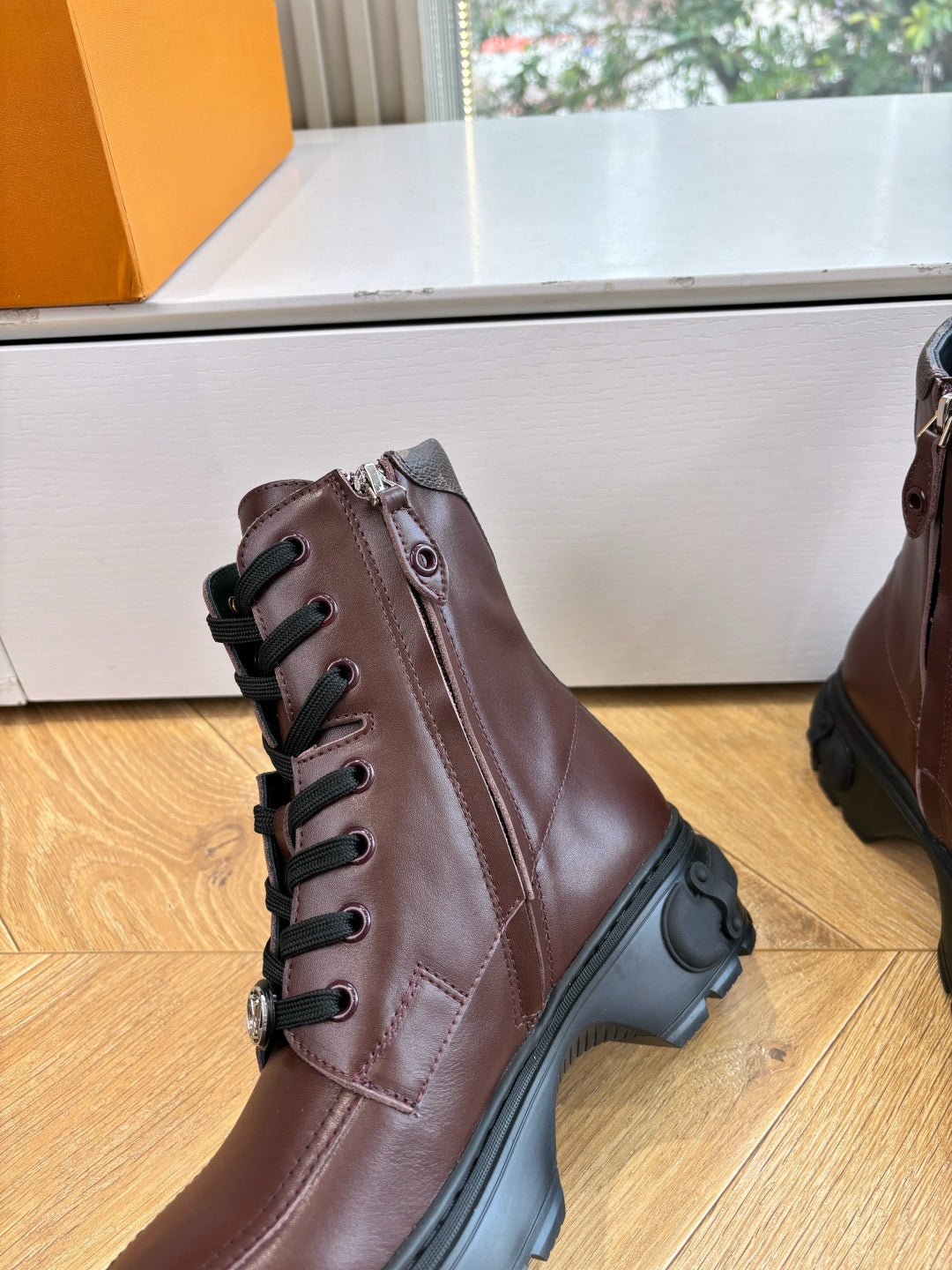 Brown leather lace-up boot with black rubber sole and side strap detail