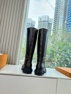Pair of black knee-high leather boots with monogram panels