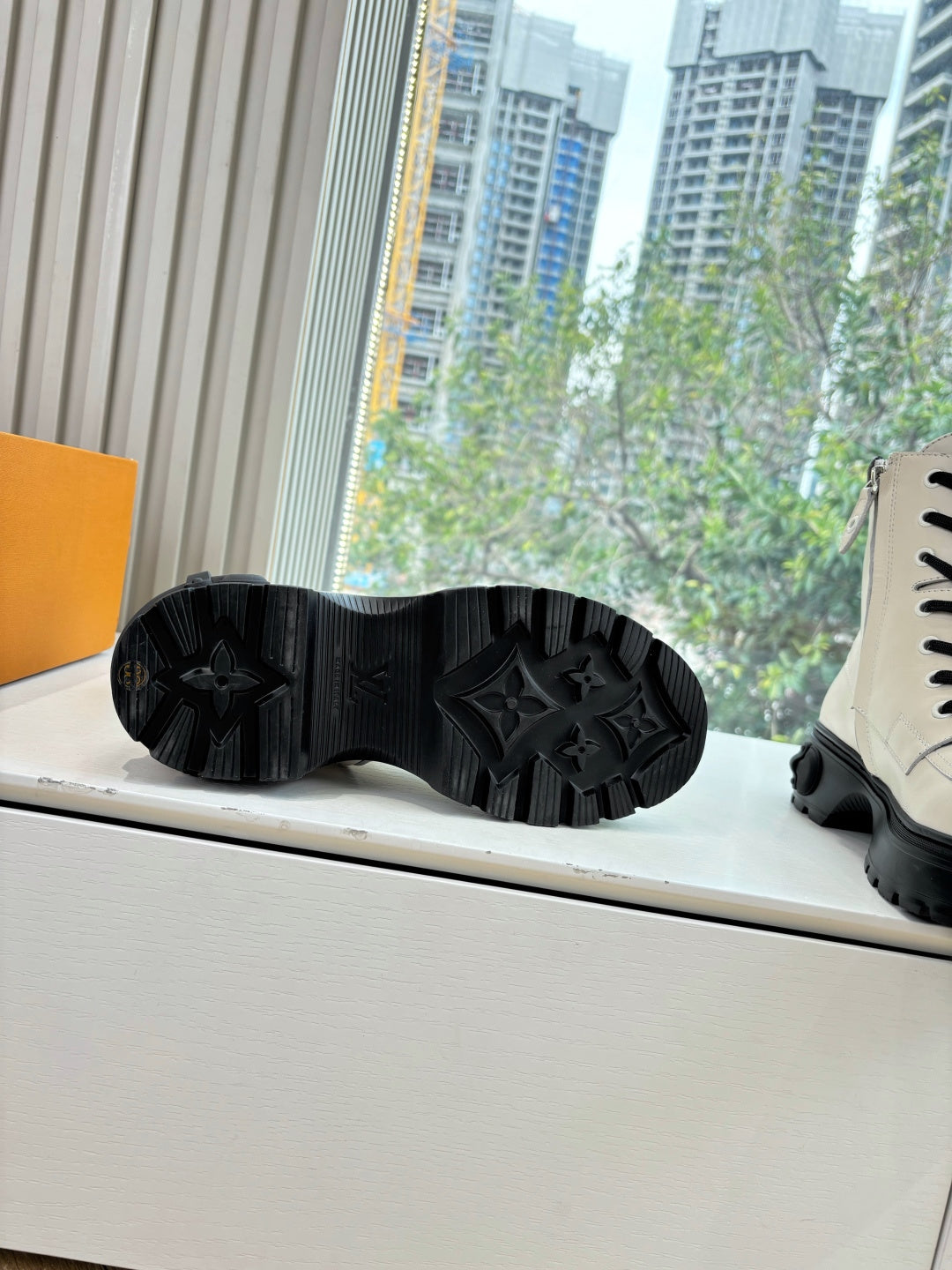 Black treaded outsoles on white leather ankle boots, with thick rubber sole