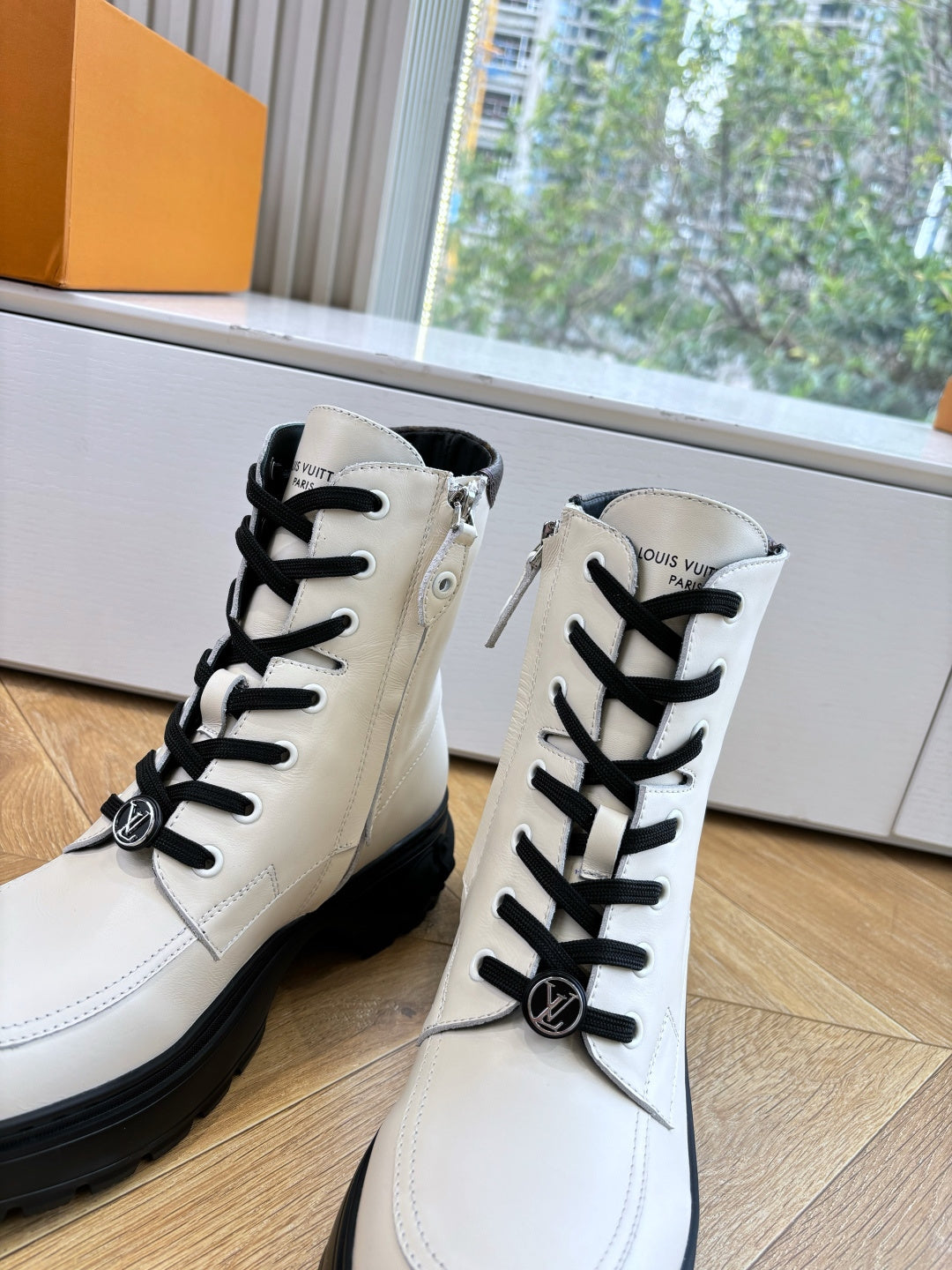 White leather ankle boots with Louis Vuitton emblem, black laces, chunky soles