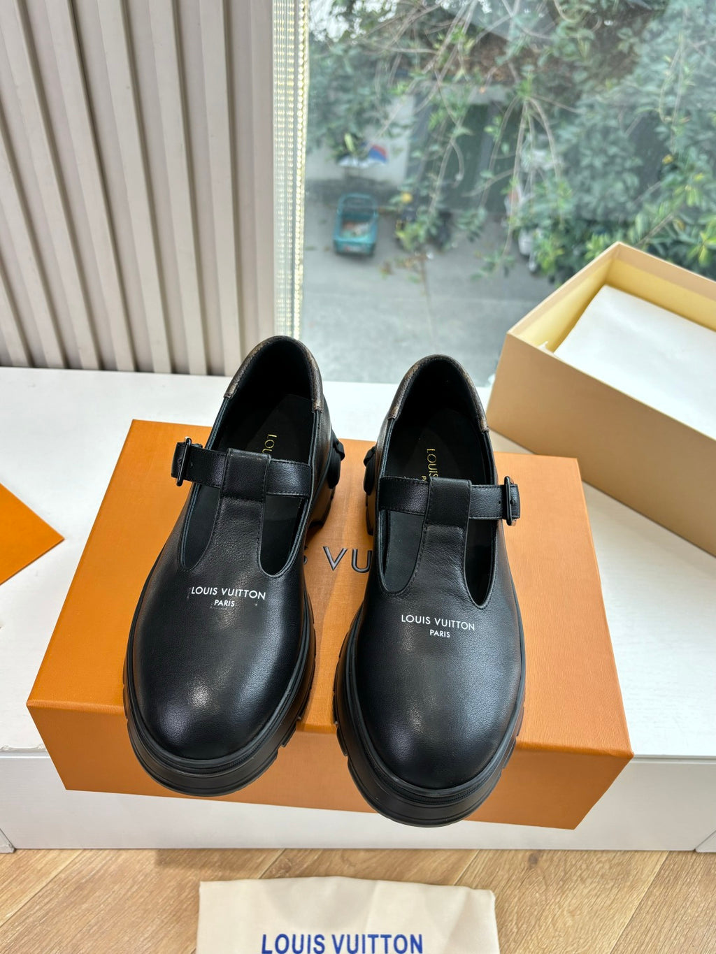 Louis Vuitton leather loafers, black, front view with buckle strap and logo