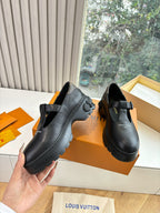 Louis Vuitton leather loafers, black, angled side view on orange shoe boxes
