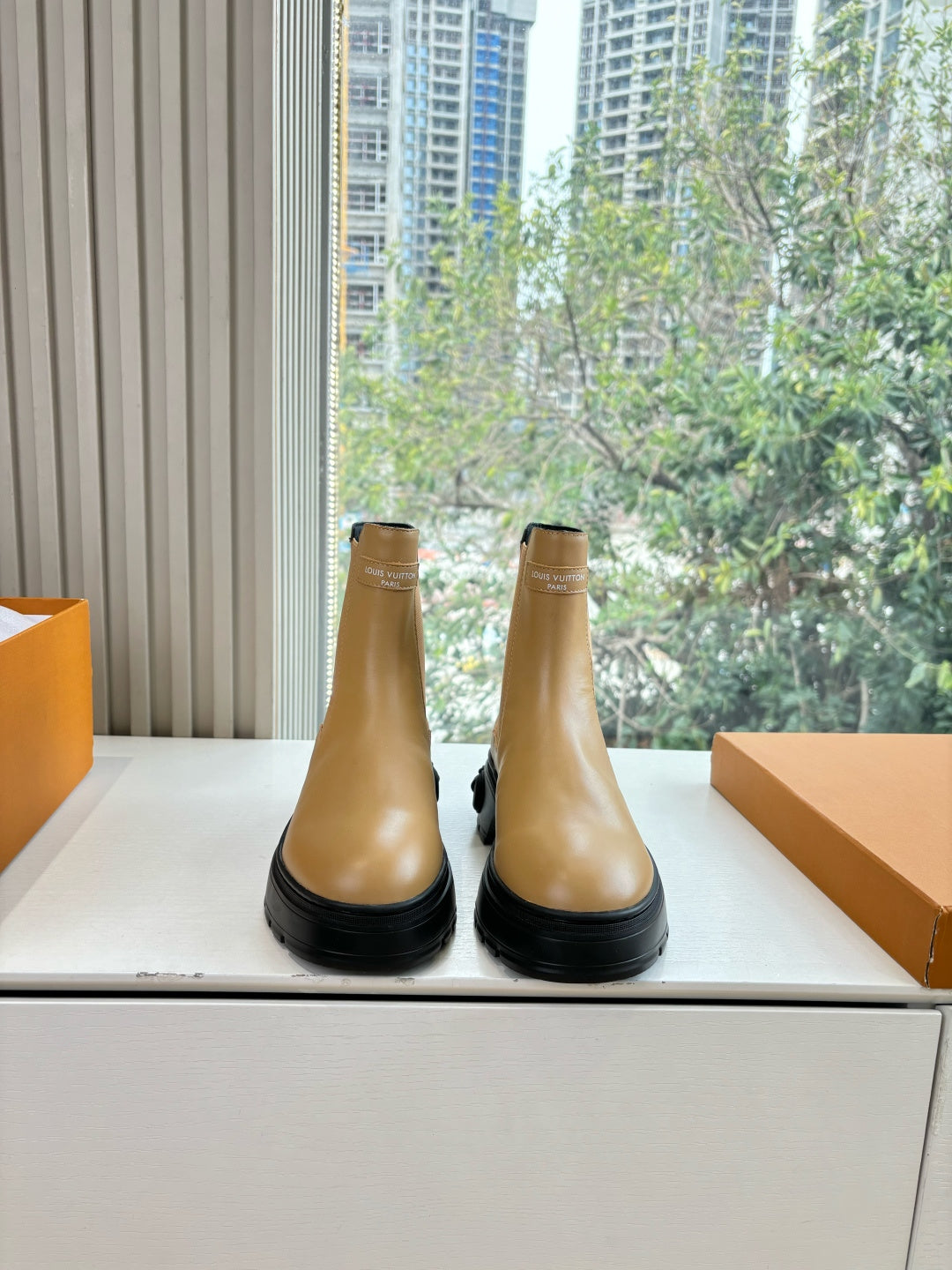 Tan leather Chelsea boots with black lug sole and elastic side panels.