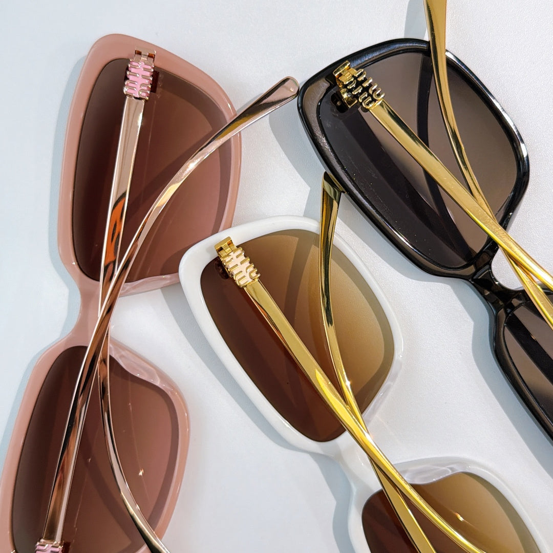 MiuMiu close-up: glossy oversized sunglasses with gold-trimmed frames and tinted lenses