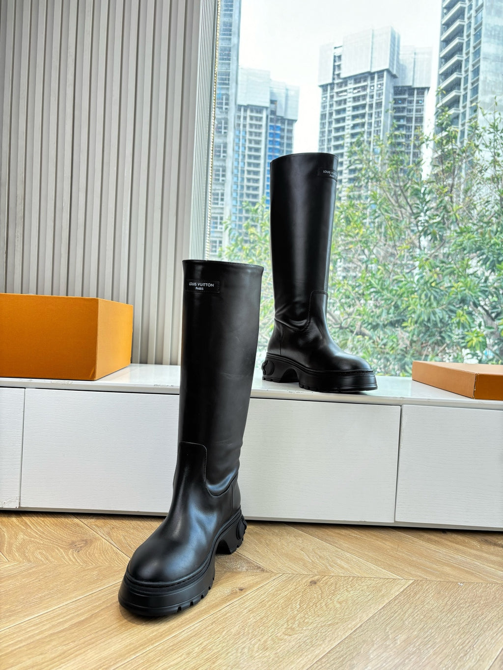 Black knee-high leather boots standing on wooden floor