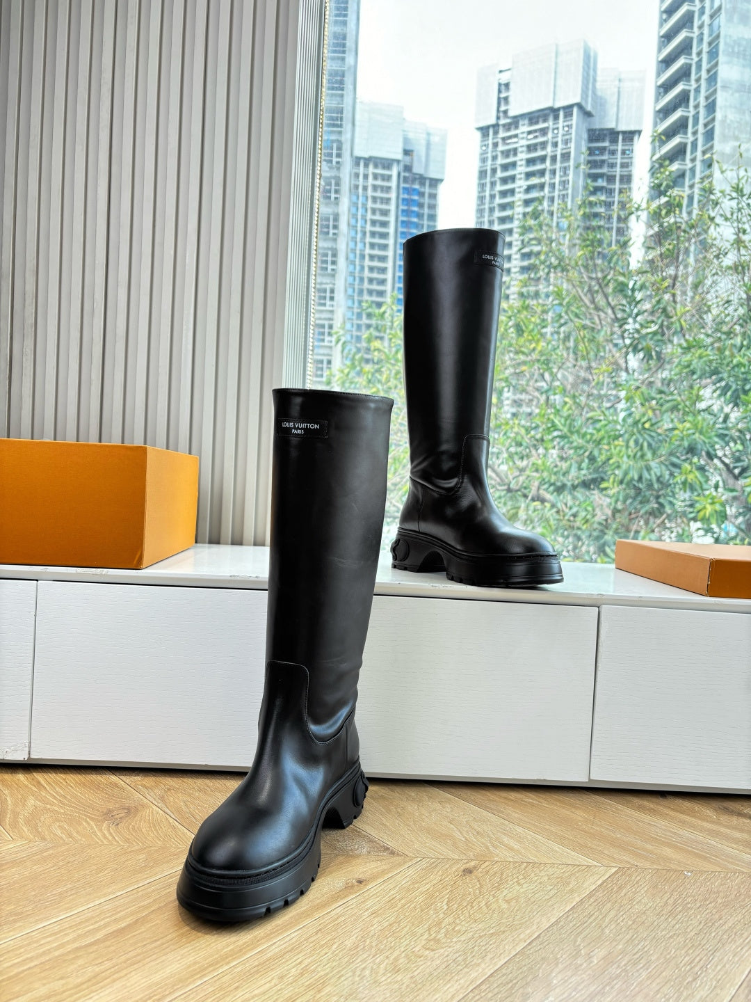 Black knee-high leather boots standing on wooden floor
