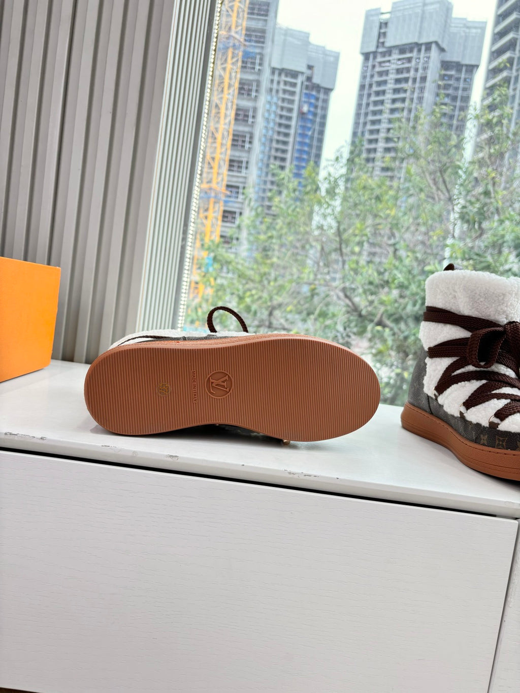 Shoe outsole with tan rubber tread and circular logo badge