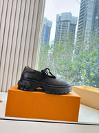 Louis Vuitton black loafer with buckle strap, side profile on orange box