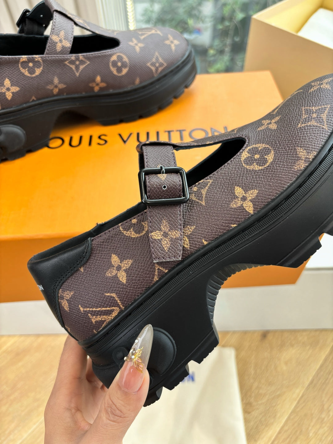 Monogram slip-on shoe close-up, dark brown canvas with black buckle and rubber sole