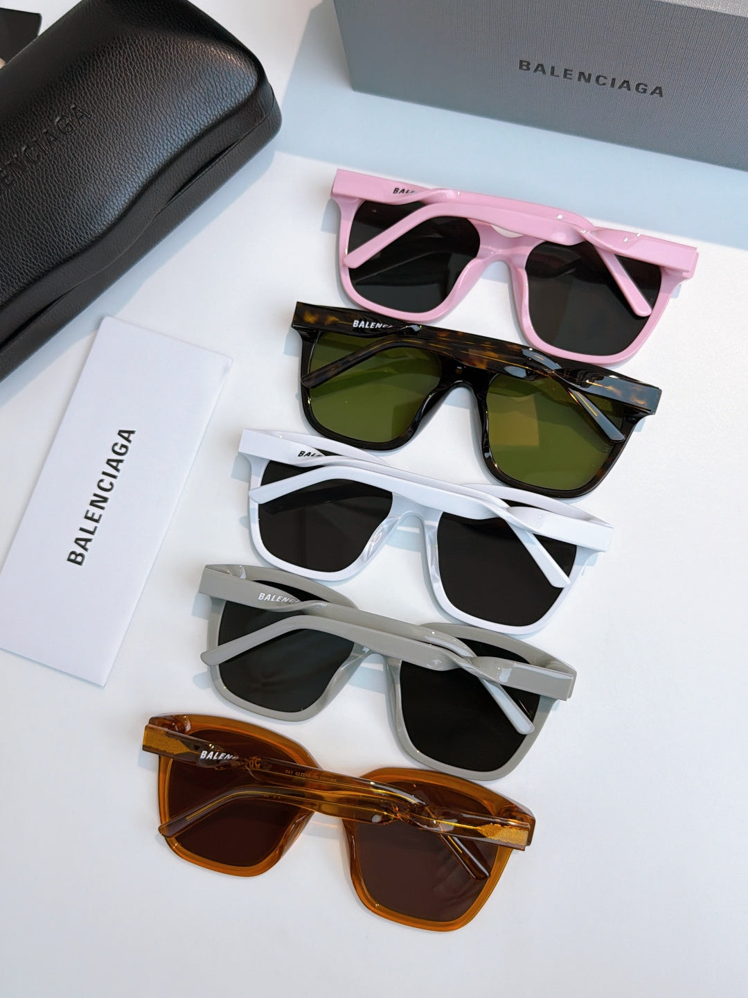 Balenciaga sunglasses set: pink, green, white, and orange frames with dark lenses.