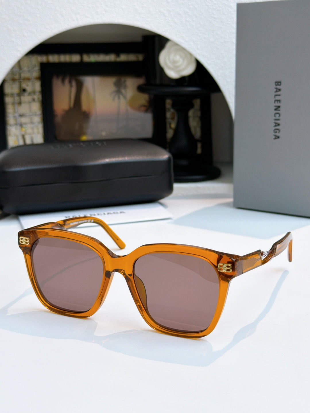 Balenciaga sunglasses with amber frames and brown lenses, square cat-eye style.