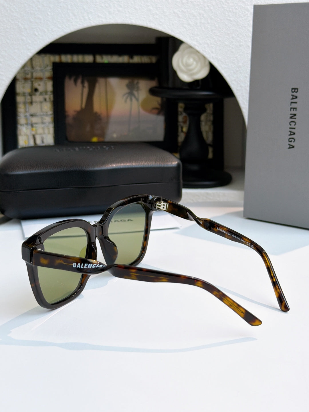 Balenciaga sunglasses with tortoiseshell frames and green-tinted lenses, side view.
