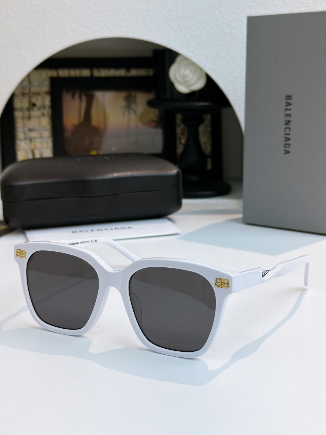 Balenciaga sunglasses with white frames and dark lenses, wide square style.
