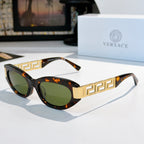 Versace cat-eye sunglasses with dark tortoise frame, gold Greek key temples, and green lenses