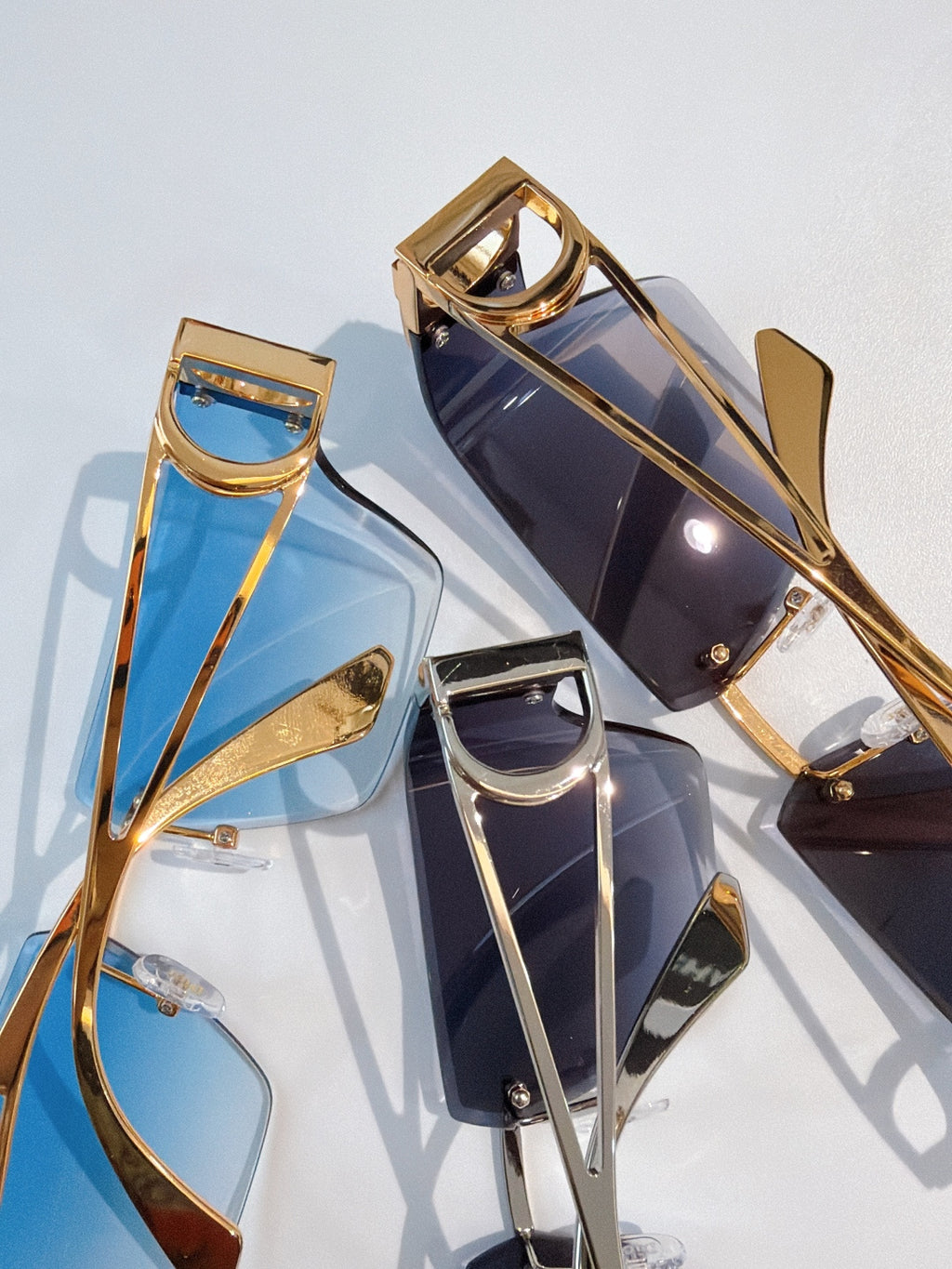 Gold-tone sunglasses with blue and dark lenses, geometric shield frames, close-up