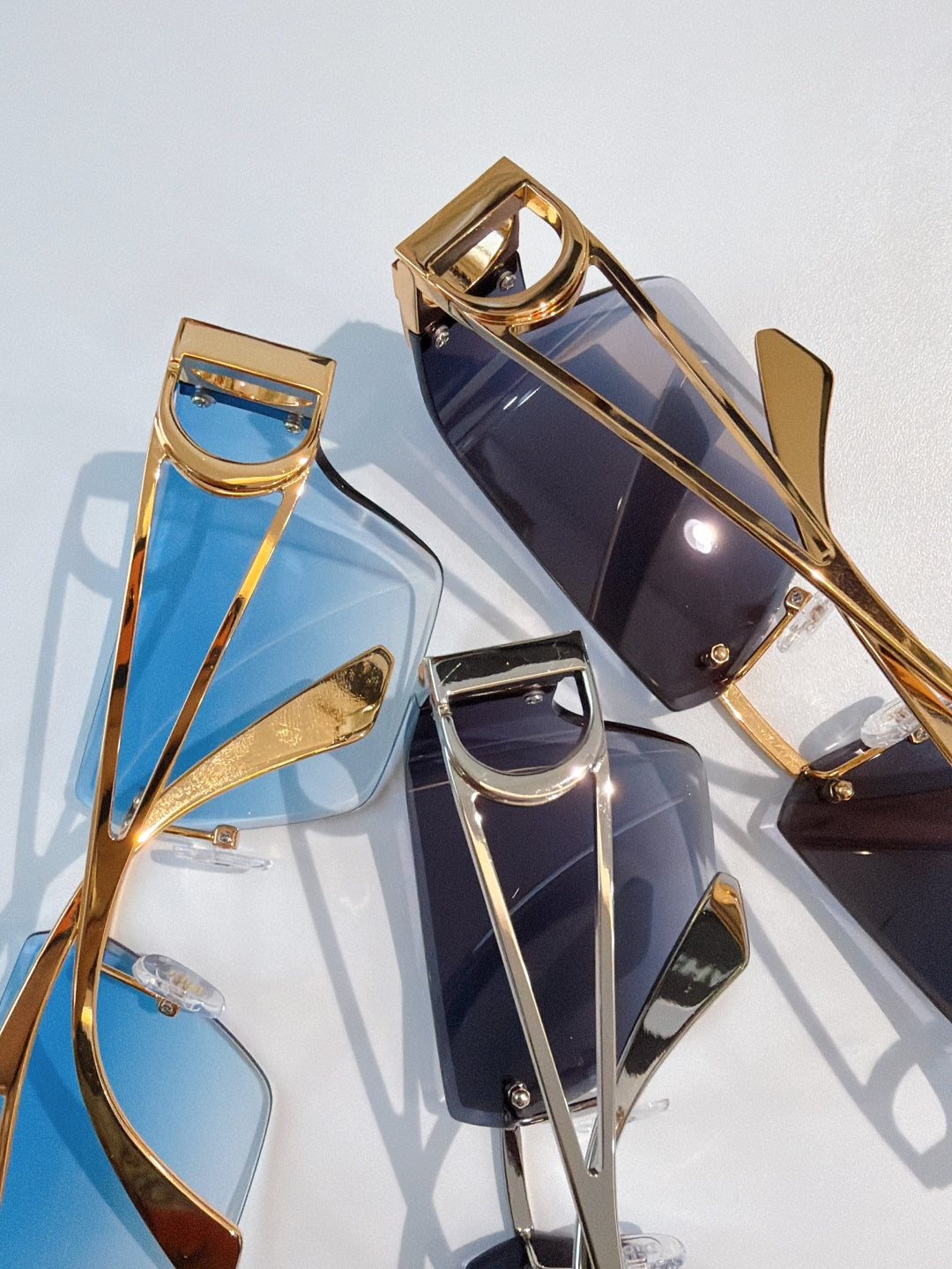 Gold-tone sunglasses with blue and dark lenses, geometric shield frames, close-up