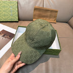 Gucci GG monogram baseball cap in dark green held in hand, curved brim visible