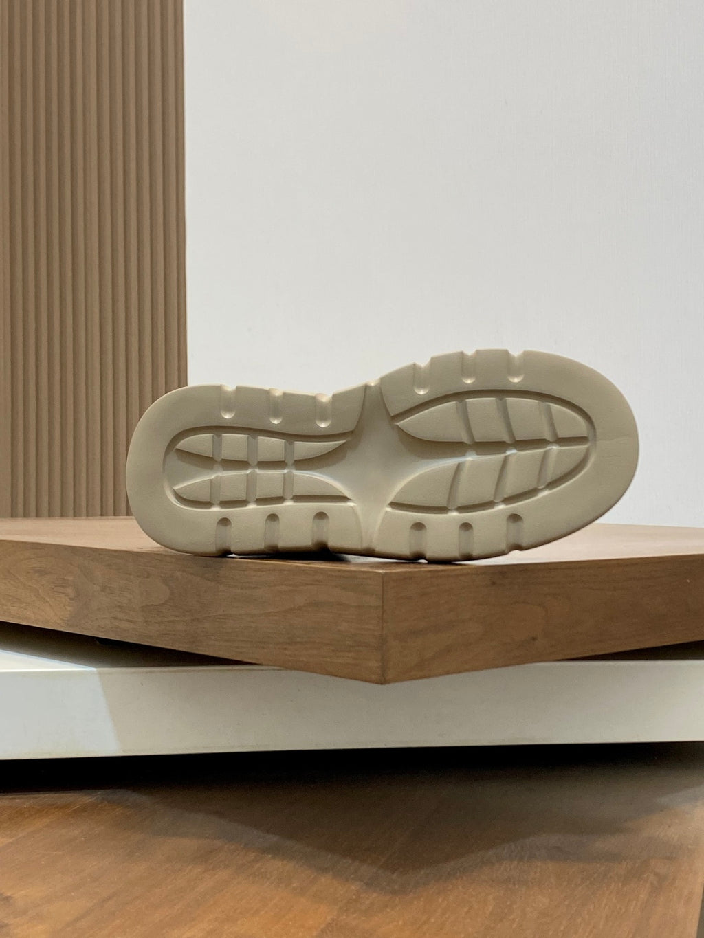 Black sneaker outsole with tread pattern and beige rubber sole