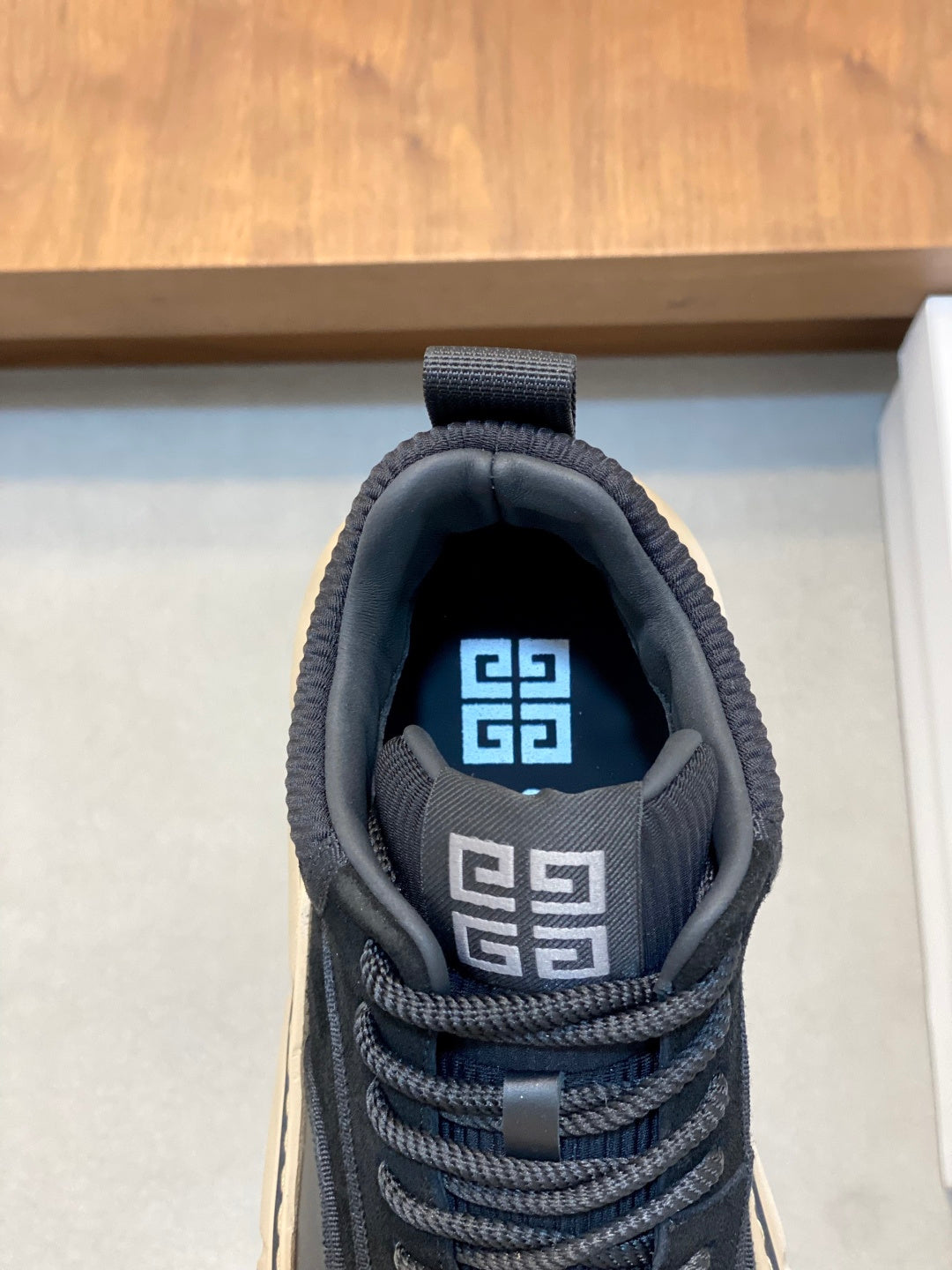 Black sneaker tongue with Greek-letter logo and blue fabric lining