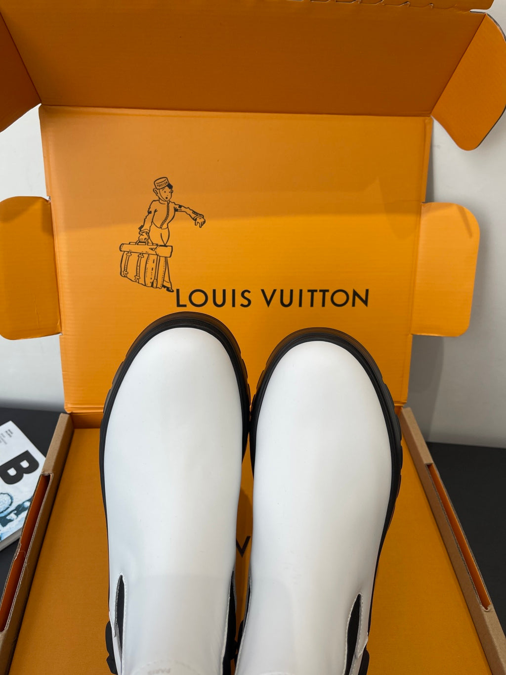 Pair of white pull-on chelsea boots with black elastic side panels