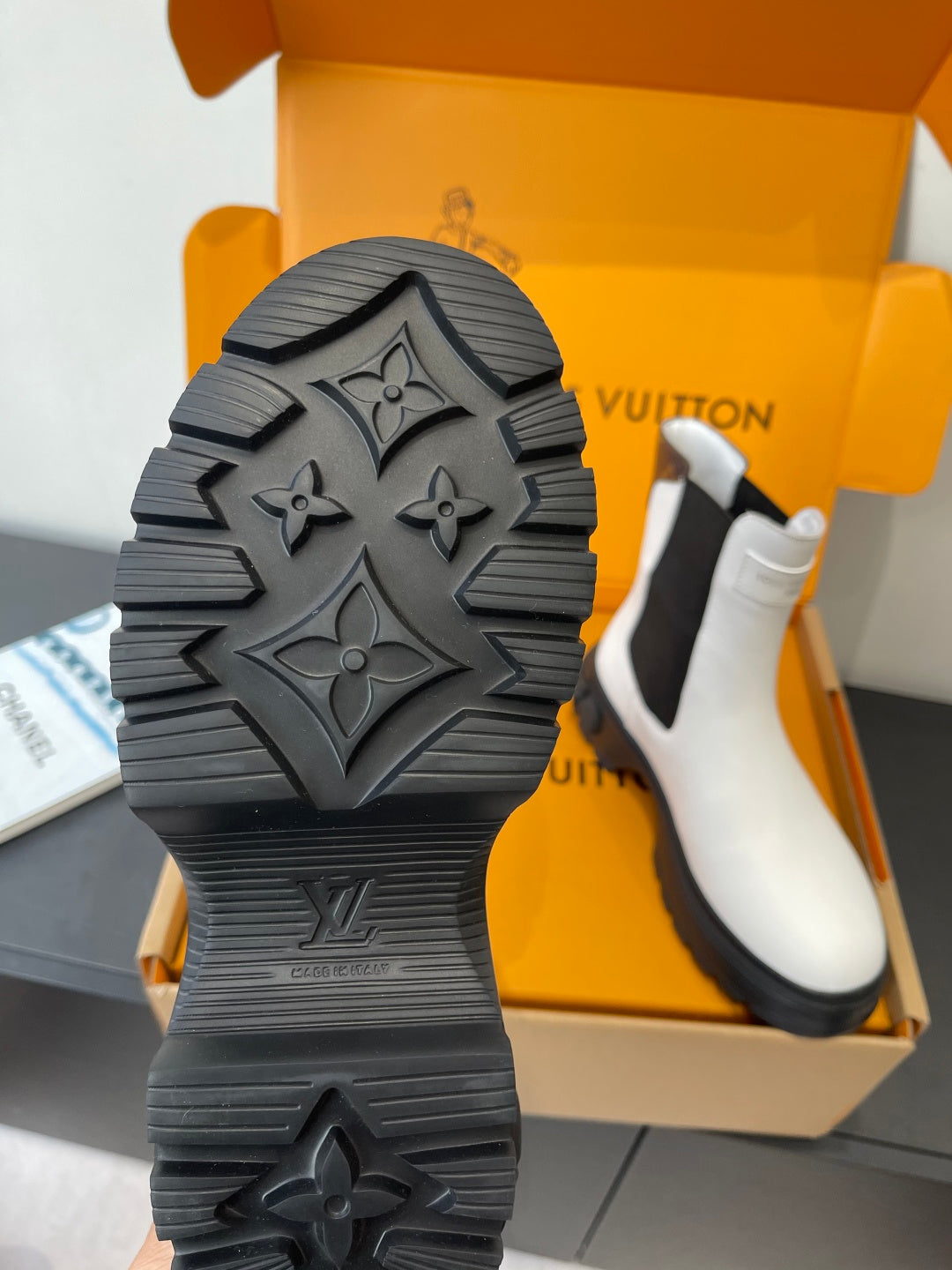 Chunky rubber lug sole with embossed emblem pattern on a white chelsea boot