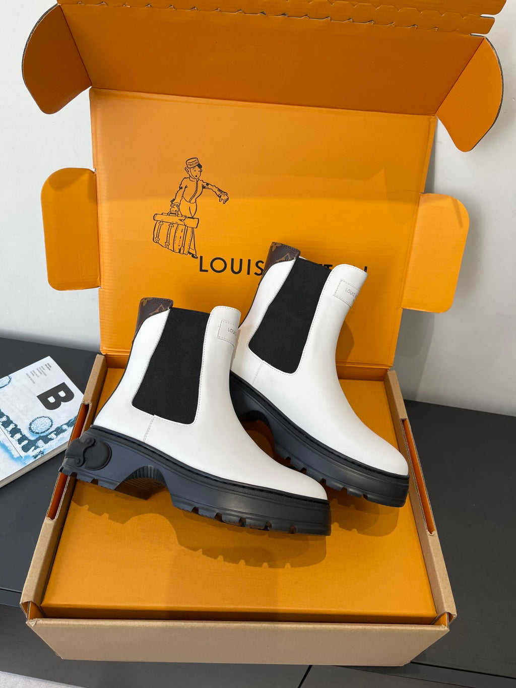 Pair of white chelsea boots with black elastic inserts and thick black lug soles