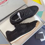 Black suede lace-up sneakers with Prada patch and gum sole, low-profile silhouette.