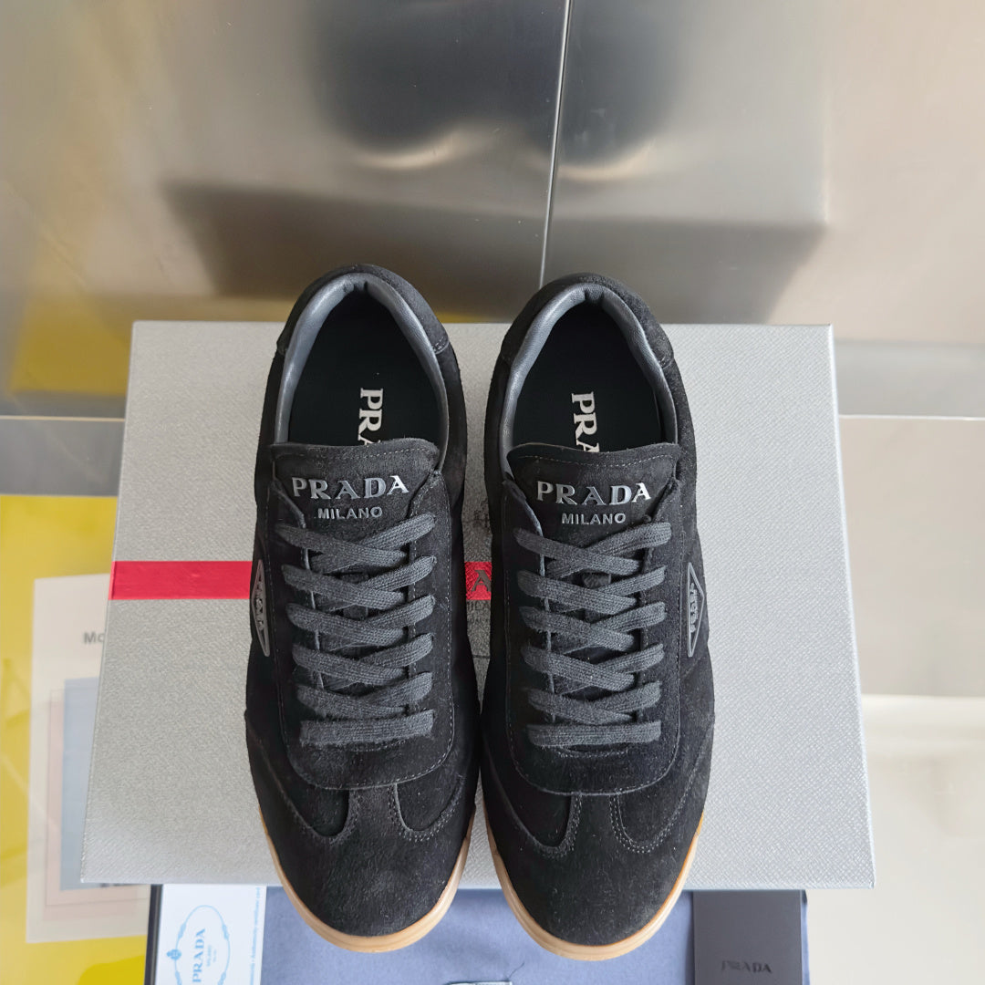Black lace-up low-top sneakers with Prada Milano branding and gum rubber sole.