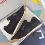 Black suede low-top sneakers, lace-up with Prada tag, gum sole detail.
