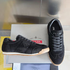 Black lace-up low-top sneakers with Prada label and gum sole, suede texture.