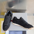 Black low-top suede sneakers with lace-up front and gum rubber sole, Prada branding.