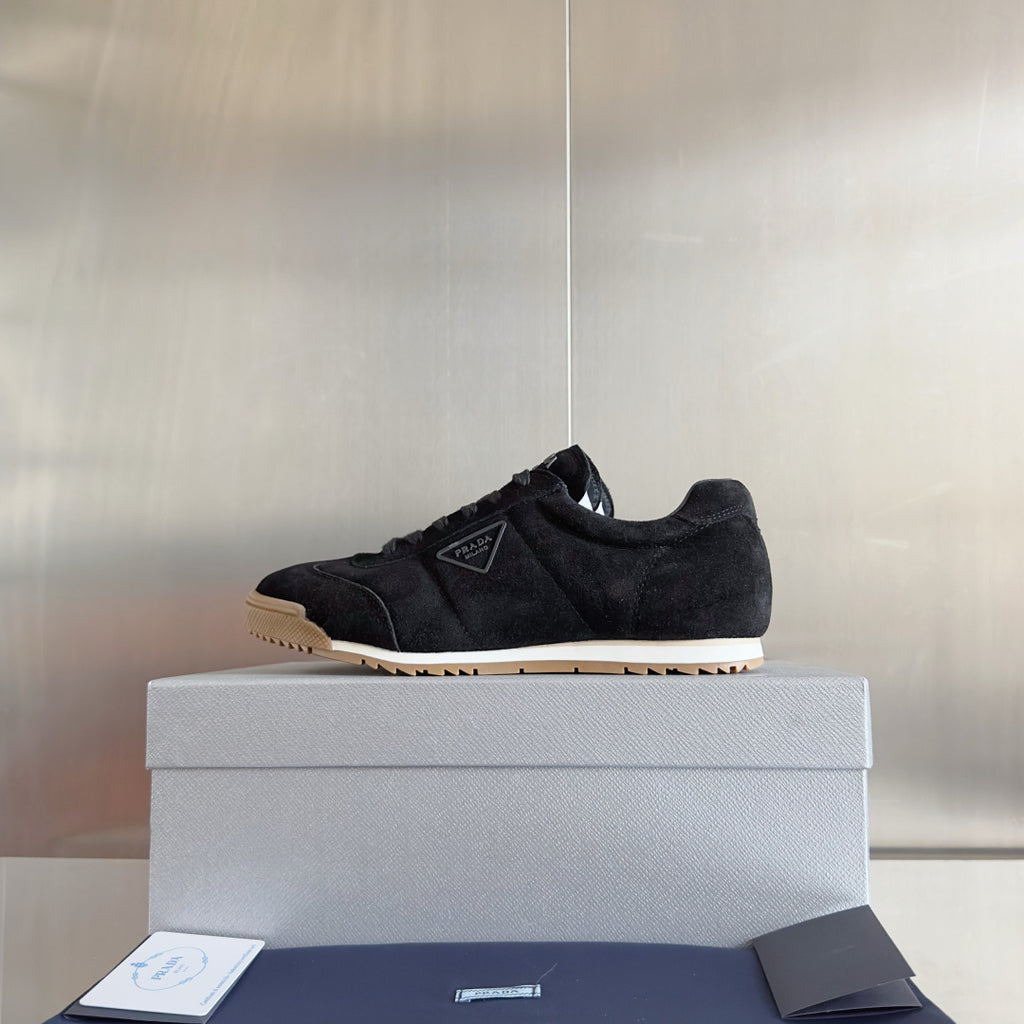 Black suede lace-up sneakers with gum rubber sole and Prada tag, low-top style.