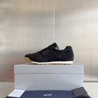 Black suede lace-up sneakers with gum rubber sole and Prada tag, low-top style.