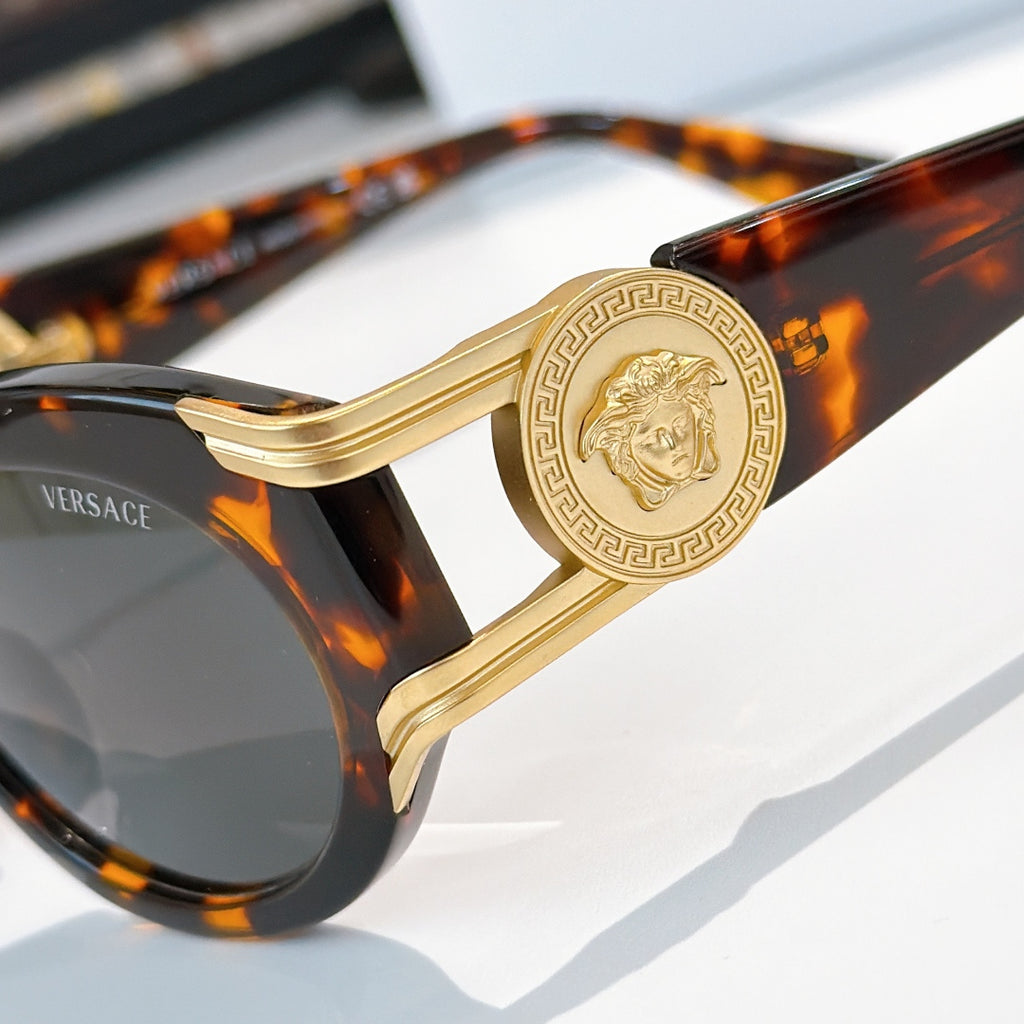 Close-up of round sunglasses with tortoise frame, gold-tone hinge detail, and dark lenses