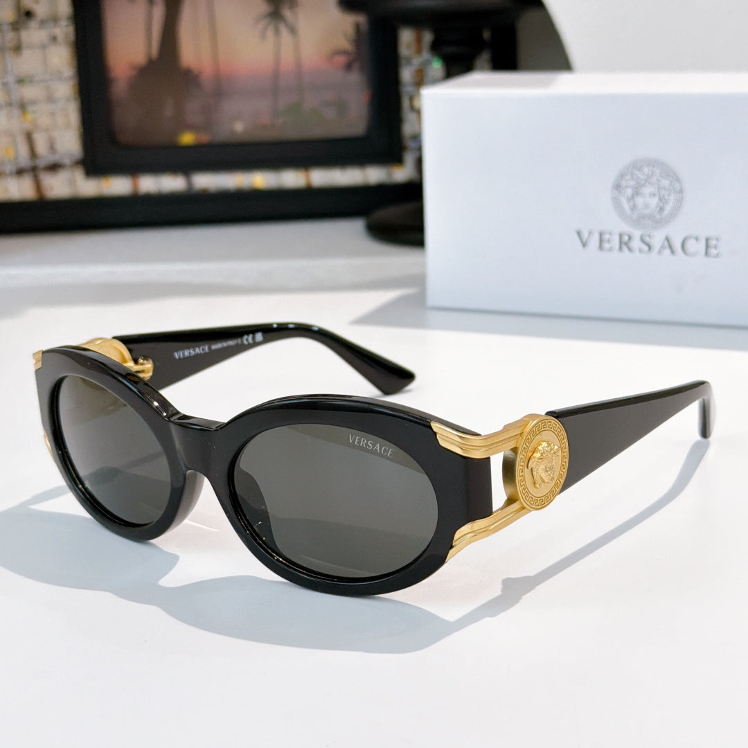 Round sunglasses with black frame, gold-tone arms, and dark gray tinted lenses