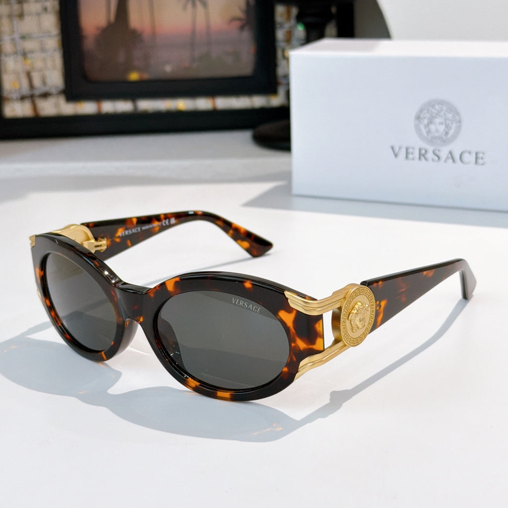 Round sunglasses with dark tortoise patterned frame, gold-tone arms, and dark gray tinted lenses