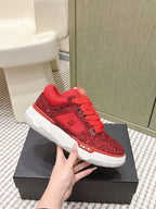 Red glitter low-top sneakers with lace-up front and white sole, on box