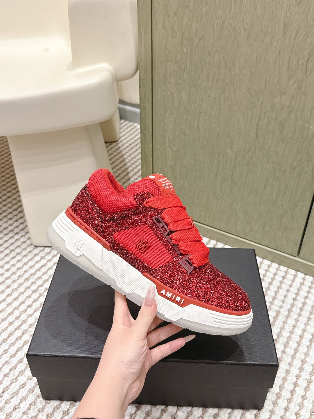 Red glitter low-top sneakers with lace-up front and white sole, on box