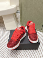Red glitter lace-up sneakers with striped white sole, on black box
