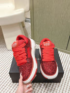 Red glitter lace-up sneakers held by hand on black box, white sole