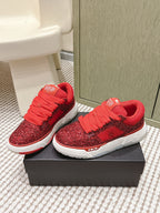 Red glitter lace-up sneakers with white sole and black side accents, on box