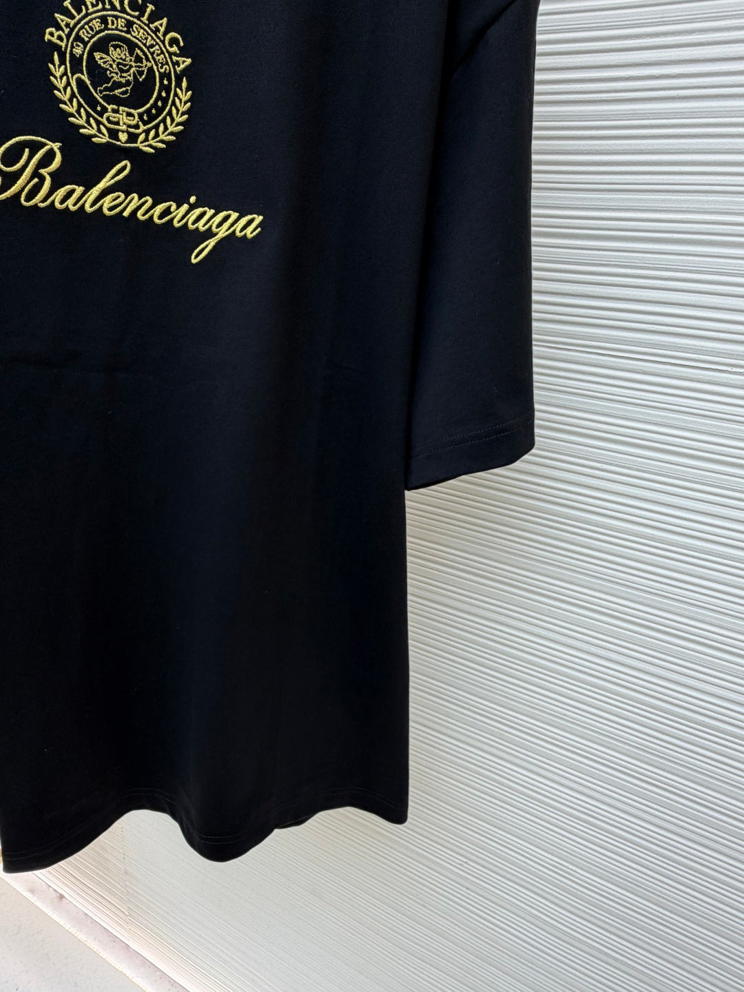 Dark short-sleeve T-shirt with gold Balenciaga script and curved hem